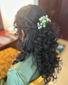 the back of a woman's head with curly hair and flowers in her hair