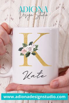 a person holding a coffee mug with the letter k on it and roses in gold