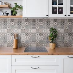 a kitchen with white cabinets and wooden counter tops has a potted plant on the stove