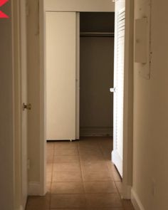 an open door leading into a hallway with tile flooring and white closet doors on either side