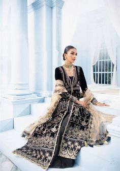 a woman sitting on top of a step wearing a black and white dress with gold accents