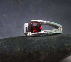 This ring has a tension set garnet . The stone is 6mm in size. The ring is hammered and hardened so that the silver securely holds the garnet. It is available in sizes 5 through 9. Other stones available are citrine, amethyst, peridot, cz, garnet mozambique and rhodolite. Please specify ring size and stone preference. The stone is snuggled down inside the two side bars and the outside bar is pressed up on the outside to protect the stone. The stone looks like it is floating in the mounting but i Outside Bar, Red Gemstone Ring, Hammered Band, Blue Topaz Earrings, Red Gemstones, Set Ring, Topaz Earrings, Modern Ring, Ring Minimalist