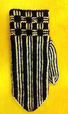 a black and white striped oven mitt hanging on a yellow wall