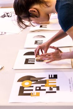 a woman is bending over to pick up something from the floor on top of some posters