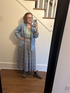 a woman taking a selfie while standing in front of a stair case and looking at her phone