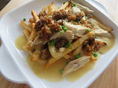 a white plate topped with pasta and meat covered in sauce on top of a wooden table