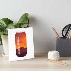 a can of beer sitting on top of a table next to a potted plant