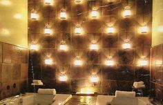 a bath room with two sinks and lights on the wall