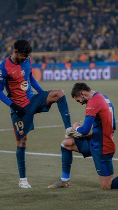 two soccer players are on the field during a game, one has his foot on the ground