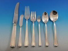 an assortment of silverware including forks, knives and spoons on a blue background