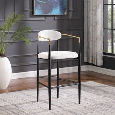 a black and white bar stool in front of a painting on the wall with a potted plant next to it