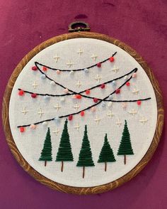 a hand embroidered christmas ornament hanging on a wall next to a purple wall