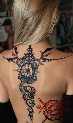 the back of a woman's neck with an intricate tattoo design on her shoulder