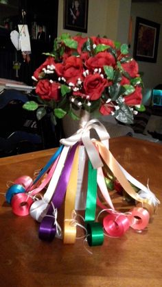 a vase filled with roses and ribbons on top of a wooden table in a living room