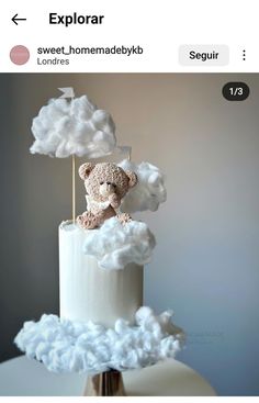 a teddy bear sitting on top of a cloud covered cake