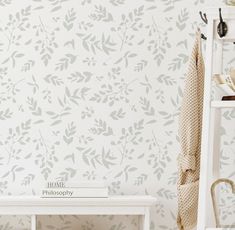 a white bench sitting in front of a wall with leaves on it's side