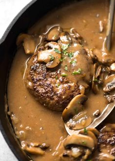 a pan filled with meat covered in mushroom gravy and a ladle full of mushrooms