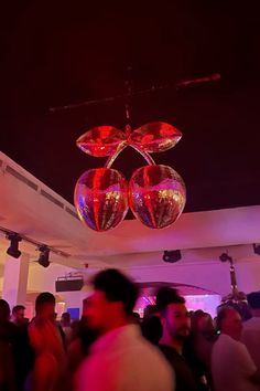 a group of people standing around in a room with disco balls hanging from the ceiling