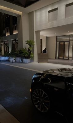 a black sports car parked in front of a building at night with its lights on