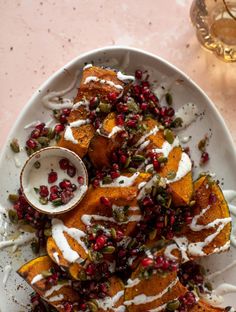 a white plate topped with sweet potatoes covered in pomegranate and whipped cream