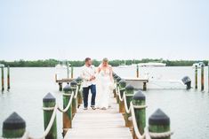 a bride and groom walking on a dock