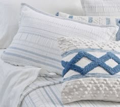 a bed with white and blue pillows on top of it