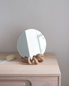 a mirror sitting on top of a wooden dresser next to a toothbrush and brush