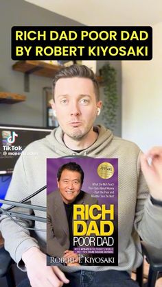 a man holding up a book in front of him with the title rich dad poor dad by robert kiyosaki