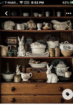 an old wooden cabinet filled with dishes and figurines on it's shelves