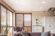 a living room filled with furniture and windows covered in wooden slatted shutters