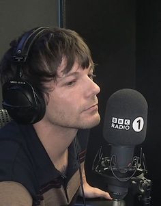 a man with headphones on sitting in front of a microphone and wearing headphones