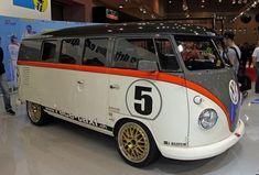 an old vw bus is on display in a showroom with people looking at it