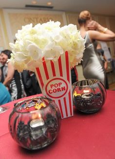 two vases filled with white flowers sitting on top of a red cloth covered table