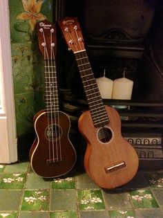 two ukulele sit side by side in front of a fireplace