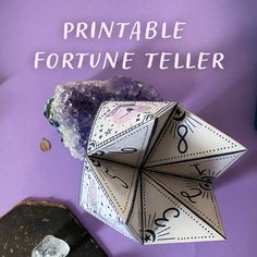 an origami fortune teller sitting on top of a purple table next to some rocks