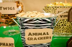 an animal cracker is in a bucket on a table with other snacks and desserts