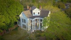 an aerial view of a white house surrounded by trees