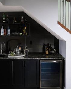 a kitchen with an oven, sink and counter space under the stairs leading up to the second floor