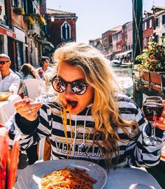 a woman eating spaghetti at an outdoor restaurant