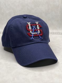 This is a navy America USA adjustable dad hat that is hand embellished with genuine red, crystal & sapphire blue Swarovski crystals on the front logo. This hat features over 150+ smaller Swarovski crystals.  - 100% Cotton - Matching fabric strap & buckle  - One Size Fits All - Raised Embroidered Logo - 150+ Swarovski Red , crystal & sapphire blue crystals individually placed by hand - Ready to ship in 1 week from San Diego, CA Bling Hat, Dodger Hats, Fabric Strap, Beautiful Hats, Sapphire Blue, Custom Hats, Dad Hat, Baseball Caps, Black Crystals