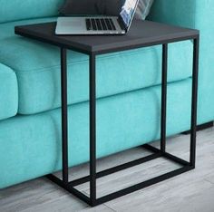 a laptop computer sitting on top of a black table next to a blue couch in a living room