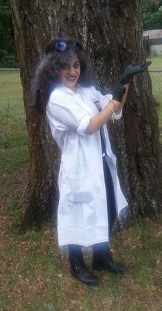 a woman dressed in costume standing next to a tree