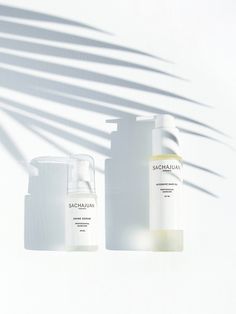 three bottles of skin care sitting next to each other in front of a white wall