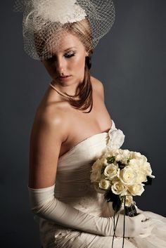 a woman in a white dress and veil holding a bouquet of flowers with her hands