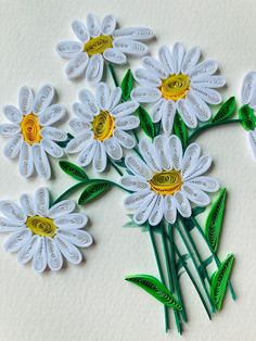 white flowers with green stems and yellow centers sitting on a table next to each other