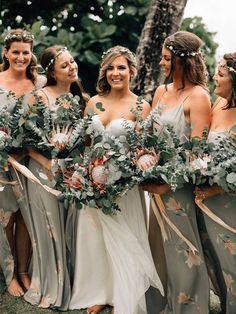 a group of women standing next to each other wearing dresses and holding bouquets in their hands