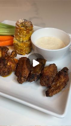 a white plate topped with meat and veggies next to a bowl of ranch dressing