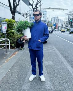 a man in blue is holding a potted plant