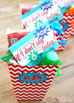 three red, white and blue gift bags with candy in them on a wooden table