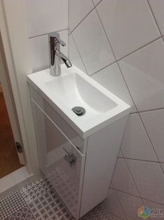 a white sink in a bathroom next to a tiled wall and floor with an open door